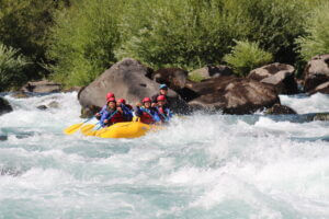 Rafting en el rápido La Escalera del río Fuy, Panguipulli, Chile. Aventureros descienden por las aguas turbulentas del río, rodeados de un impresionante paisaje de bosques y montañas